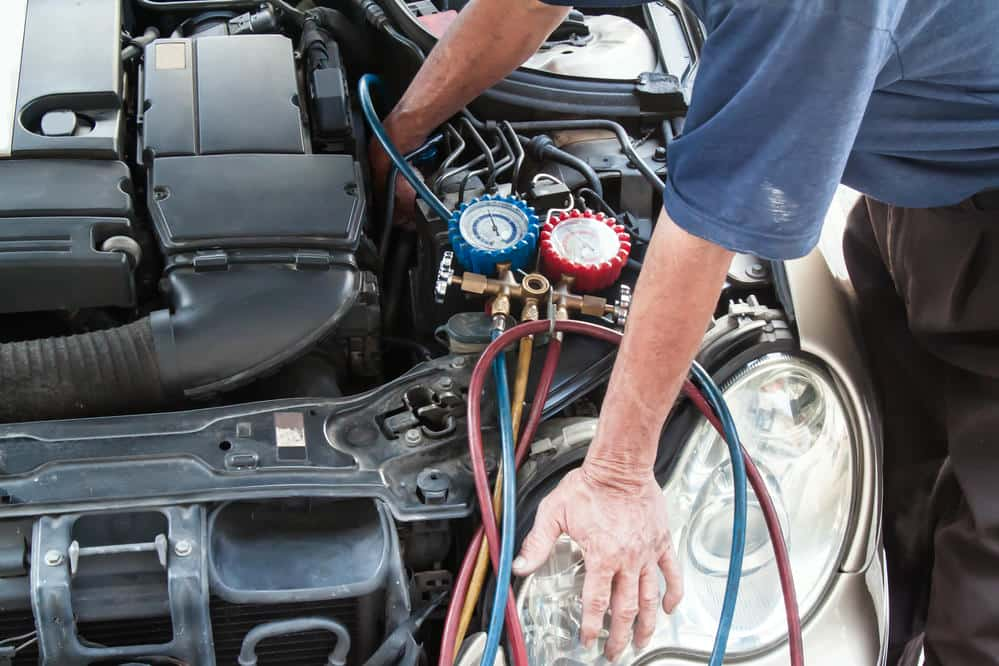 Technician refilling car air conditioning system at Dallas Complete Auto in Lancaster, Dallas, TX